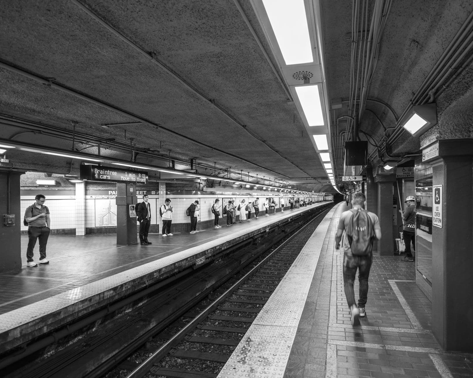 Black and white photo of a Boston subway station with people waiting on the platform.